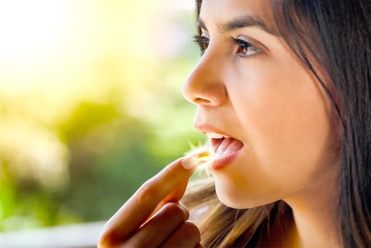 VITD3 Anwendungsfaelle Eine weibliche Person nimmt eine Weichkapsel